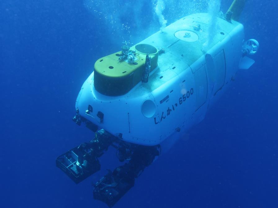 Billede af et undervandscamera, der bliver sænket ned i havet, baggrunden er blå og det hvide camera har bobler op mod havoverfalden. 